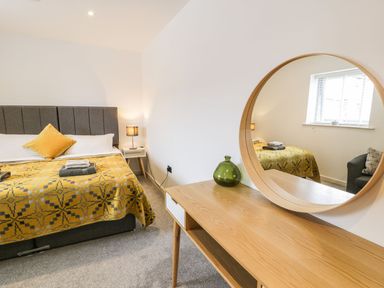 A bedroom with a bed and mirror at Cae Sam in Pentraeth