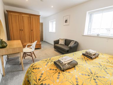 A bedroom with a bed, towels, and a wardrobe at Cae Sam in Pentraeth