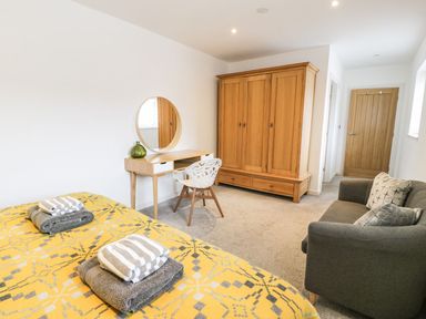 A bedroom with a bed, dresser, wardrobe and sofa at Cae Sam in Pentraeth