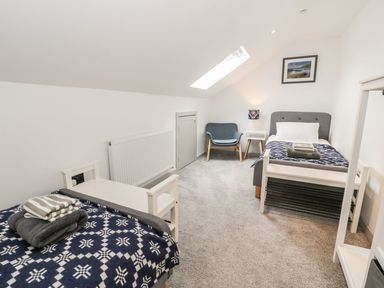 A bedroom with two beds and a chair at Cae Sam in Pentraeth