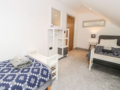 A bedroom with two beds and a shelf at Cae Sam in Pentraeth