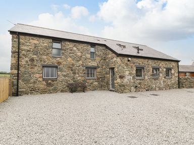 A stone house with windows and a gravel driveway at Cae Sam in Pentraeth