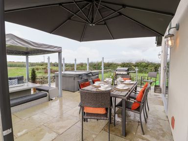 An outdoor dining area with chairs and a hot tub at Cae Sam Pentraeth
