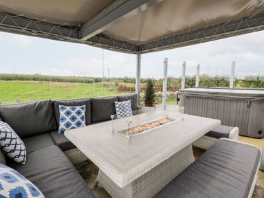 An outdoor seating area with a fire pit and hot tub at Cae Sam Pentraeth