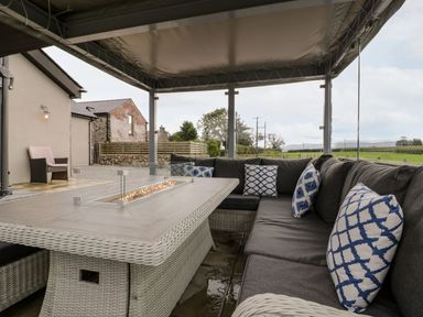 An outdoor living area with seating and a fire pit at Cae Sam in Pentraeth