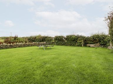 A garden with a picnic table and grass at Cae Sam in Pentraeth