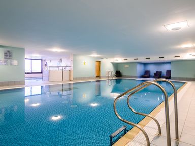 An indoor pool area with a swimming pool and lounge chairs at The Whitbarrow Den in Penrith