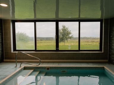 An indoor pool with a window overlooking grass and trees at Fell Side in Penrith