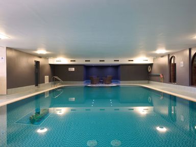 An indoor swimming pool with chairs and a table at Fell Side in Penrith