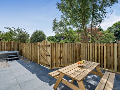 A garden with a dining table and hot tub at Klys 1.0 Spa Perranporth