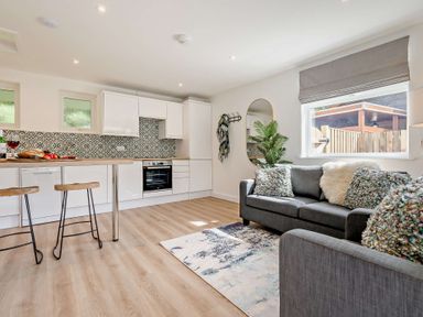 A kitchen area with white cabinets and bar stools at Klys 1.0 Spa Perranporth