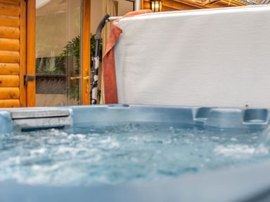A hot tub next to a wooden cabin at Piran Spa Lodge Pet Perranporth