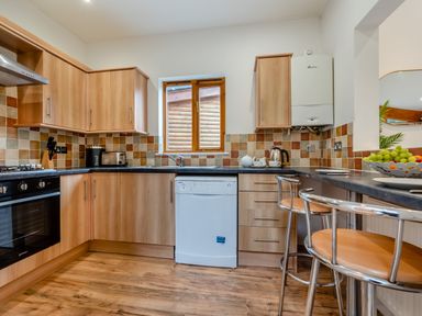 A kitchen with cabinets, countertop, dishwasher, and window at Piran Spa Lodge Pet Perranporth