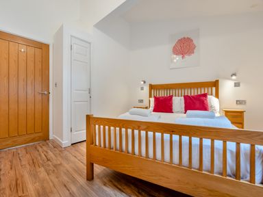A bedroom with a wooden bed and two doors at Piran Spa Lodge Pet Perranporth
