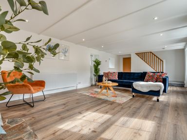 A living room with a sofa, chair, and coffee table at The Farmhouse (Pet) Perranporth