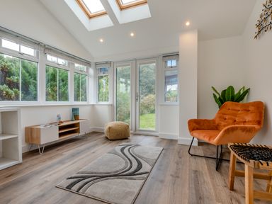 A conservatory with windows and a chair at The Farmhouse (Pet) Perranporth