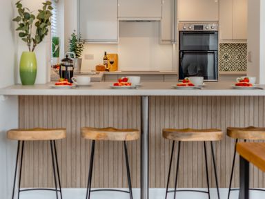 A kitchen with a counter and bar stools at The Farmhouse (Pet) Perranporth