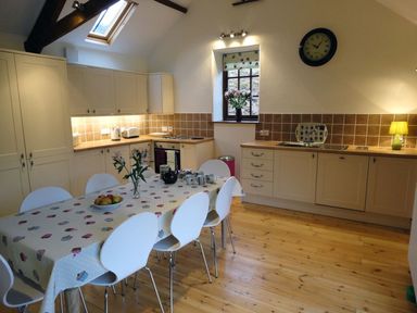 A kitchen with a dining table and chairs at Nethercote Byre in Minehead