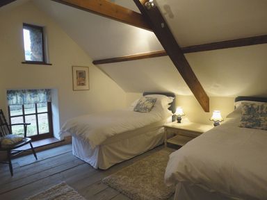 A bedroom with two beds and a window at Nethercote Byre in Minehead