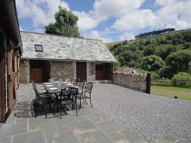 An outdoor dining area with a table and chairs at Nethercote Byre Minehead