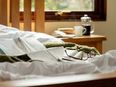 A bedroom with a bed, map, glasses, and coffee at The Derwent (Pet) Slaley