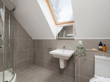 A bathroom with a shower, sink, mirror, and toilet at The Hexham in Slaley