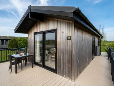 A wooden cabin with a table and chairs outside at Stokesley (Pet) Great Ayton