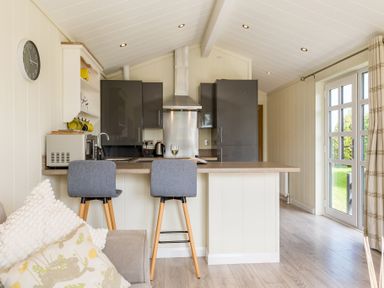 A kitchen with bar stools and modern appliances at Stokesley (Pet) Great Ayton