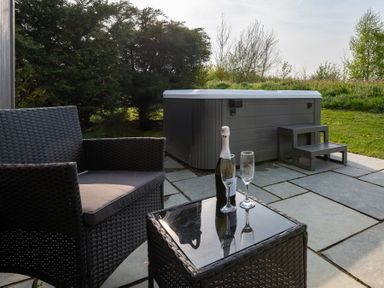 An outdoor area with a hot tub, chair, table, and drinks at Stokesley (Pet) Great Ayton