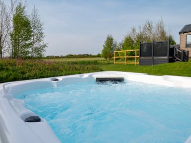 A hot tub with water and grass nearby at Stokesley (Pet) in Great Ayton