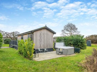 An outdoor area with a wooden cabin, table, chairs, and a hot tub at Stokesley (Pet) Great Ayton