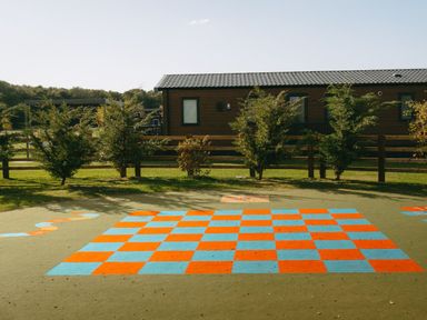A playground area with a checkerboard and trees at Greystone in Great Ayton