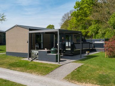 An outdoor view of a cabin with a deck and grill at The Woods in Great Ayton