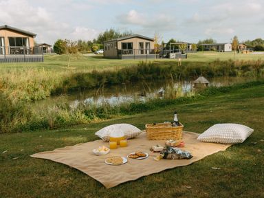A picnic setup with food and drinks near a water body at The Woods in Great Ayton