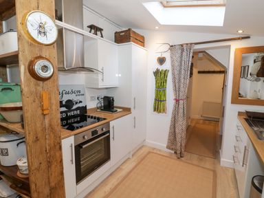 A kitchen with cabinets, oven, stove, and a rug at Flat 4 in Evesham