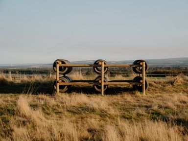 A wooden structure with tires in a grassy field at The Grays in North Berwick