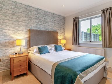 A bedroom with a bed and nightstand at 4C2 Summerleaze Garden Cottage 2 Spa in Bude
