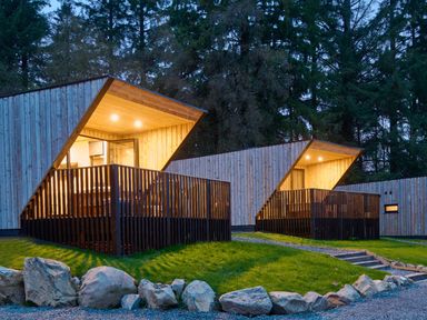 Two wooden cabins with decks and lighting at Orka 1.0 (Pet) Dumfries