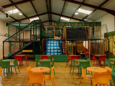 An indoor play area with a climbing structure and tables at Hurricane Lodge in Fair Oak