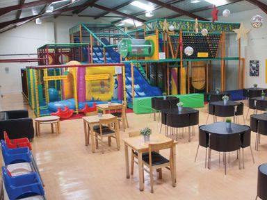 An indoor play area with tables and a play structure at Hurricane Lodge in Fair Oak