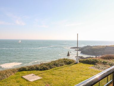 An outdoor view of the ocean with a sailing boat and a flagpole at The Old Signal House in Torpoint