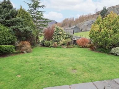 A garden with grass and various trees and shrubs at Thrang View in Chapel Stile