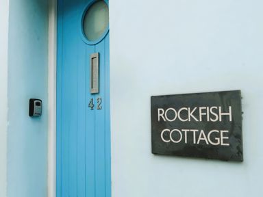 An outdoor photo of a blue door with a sign at Rockfish Cottage Brixham