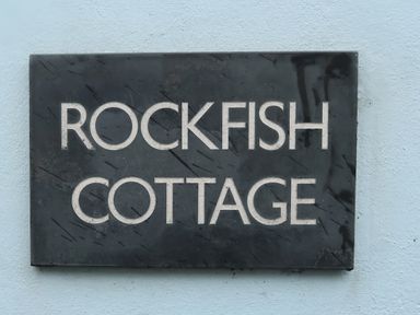 A plaque with the name Rockfish Cottage on a wall in Brixham
