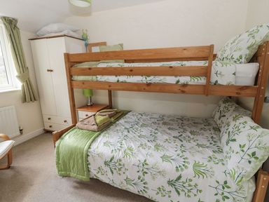 A bedroom with a bunk bed and wardrobe at Ramblers Cottage in Alnwick
