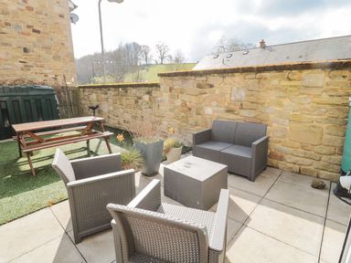 A garden with seating and a table at Ramblers Cottage in Alnwick