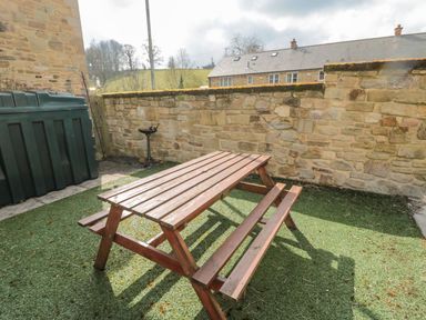 A table and benches in an outdoor area at Ramblers Cottage in Alnwick