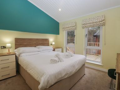 A bedroom with a double bed and windows at High Lake View Lodge White Cross Bay near Troutbeck Bridge