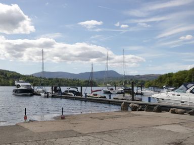 A view of boats docked at a pier with mountains in the background at High Lake View Lodge, White Cross Bay near Troutbeck Bridge