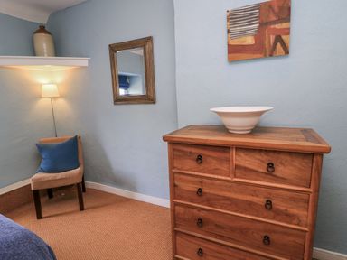 A bedroom with a dresser and chair at Ostlers in Burford